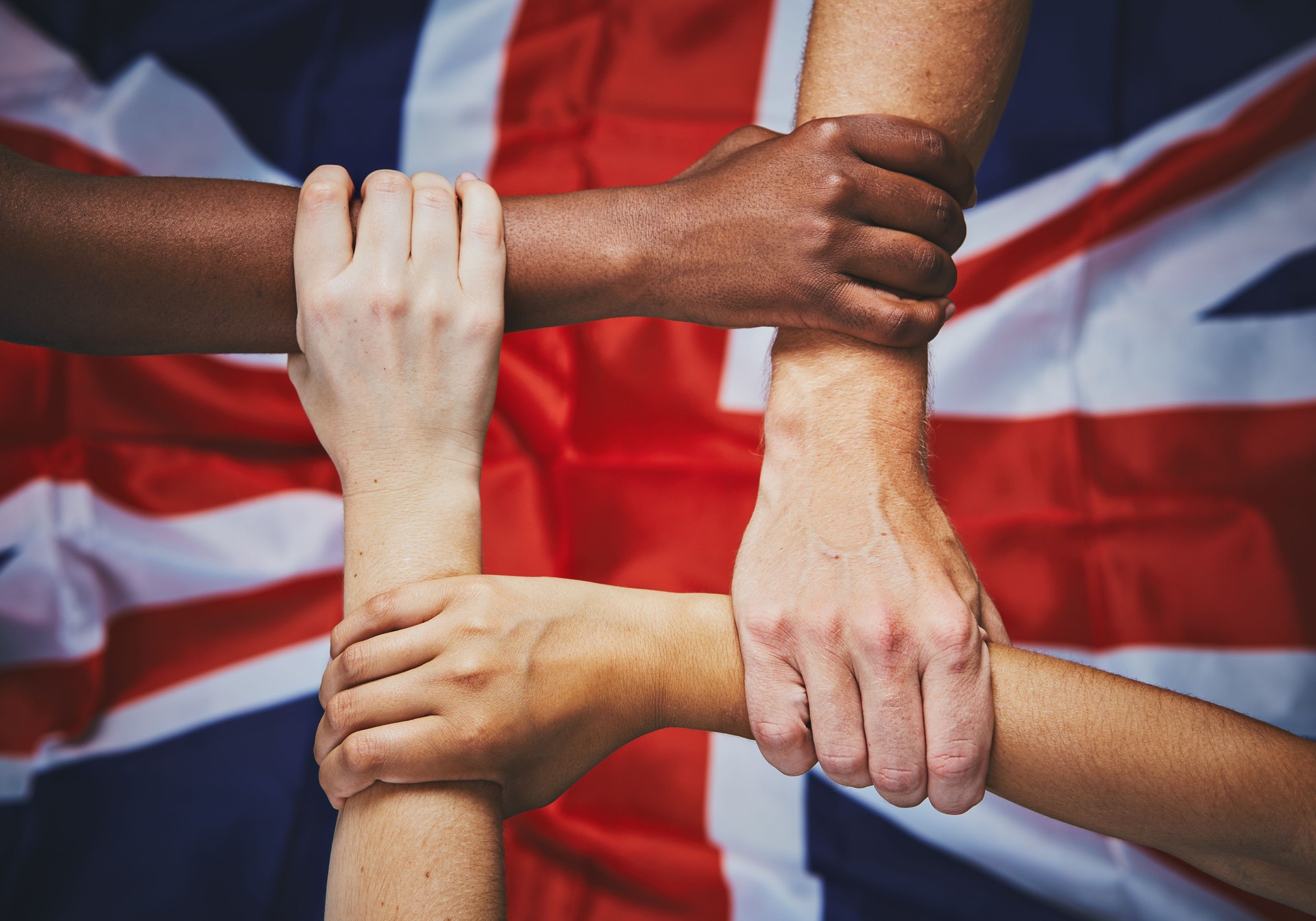 Four hands clasped in a square over Union Jack