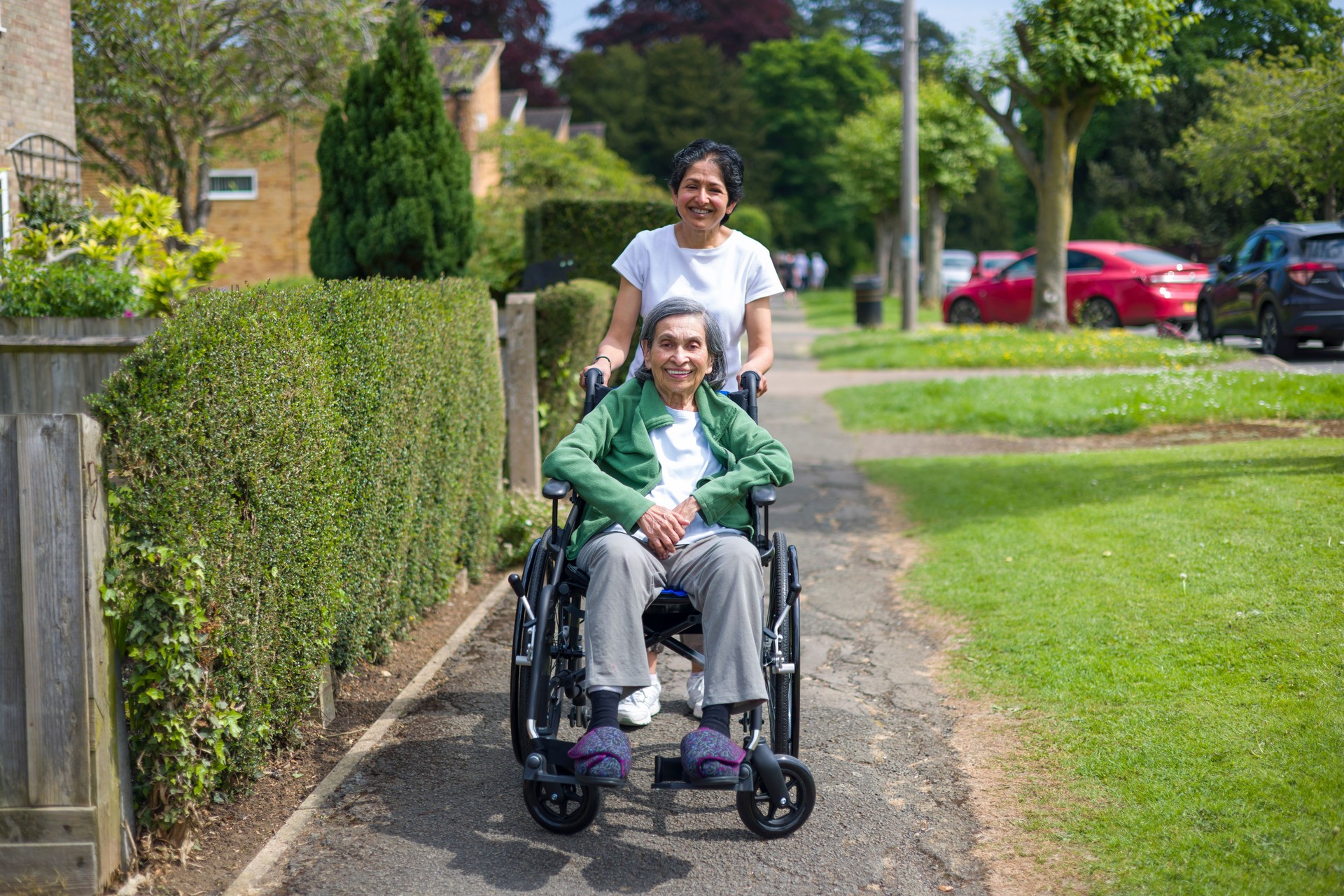 Old Indian woman in wheelchair on pavement outdoors, UK
