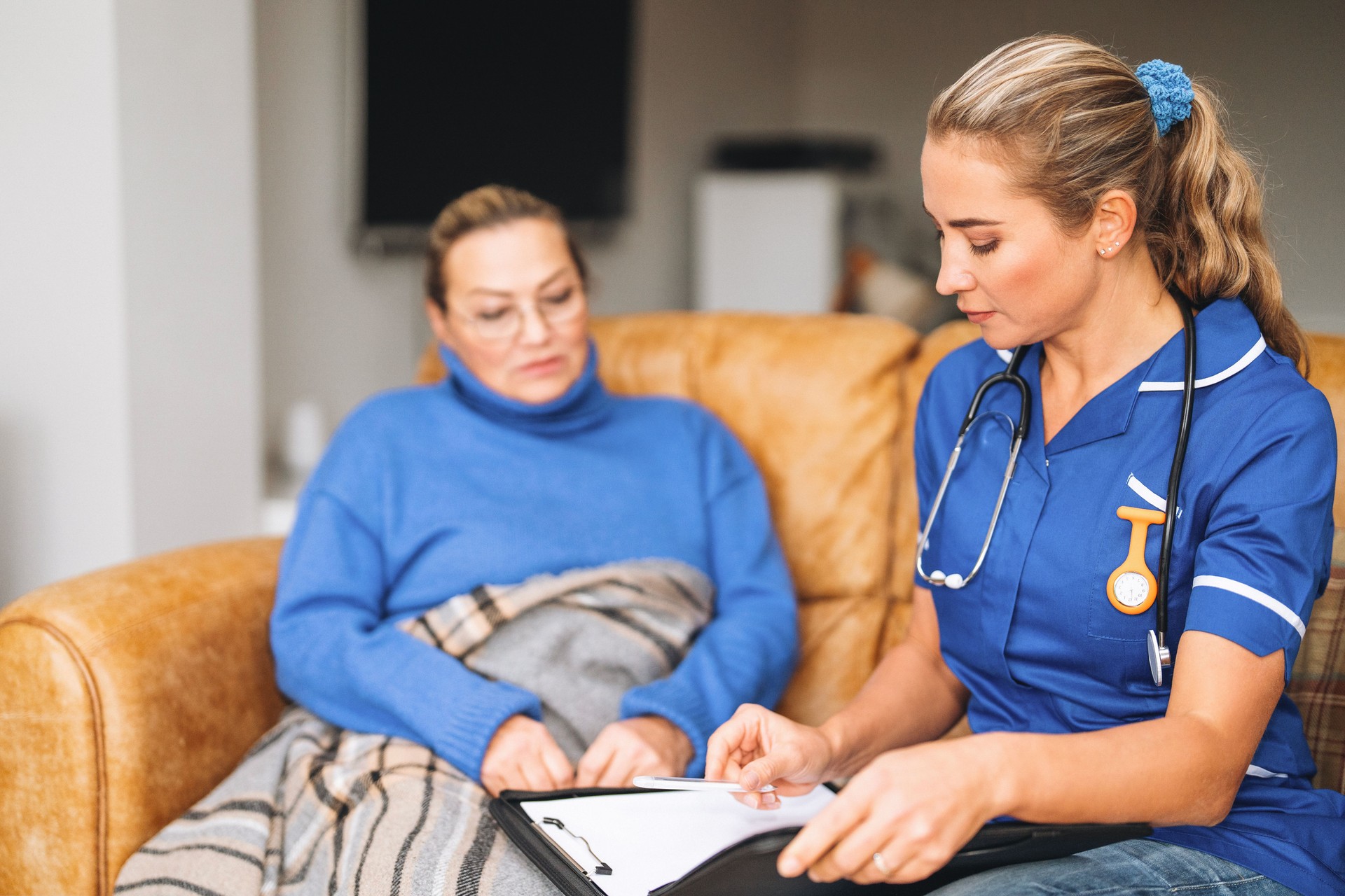 Nurse and patient engage in health discussion while seated in comfortable living room setting during the day